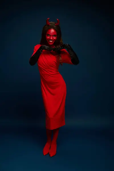 A beautiful woman showcases her devil costume, exuding charm and confidence in the dark setting. — Stock Photo