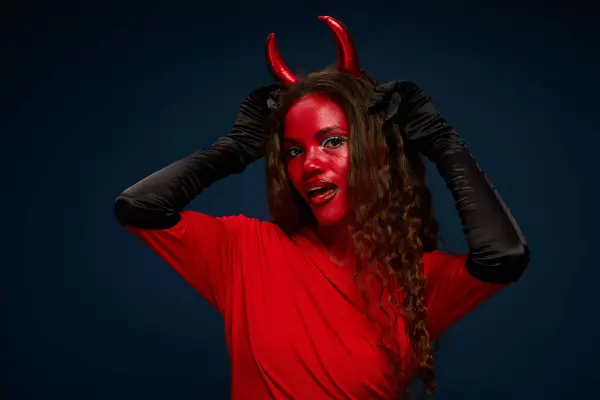 A stunning woman dressed in a devil costume enthusiastically engages in Halloween festivities. — Stock Photo