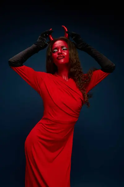 A captivating woman in a bold red costume flaunts her playful, devilish style. — Stock Photo