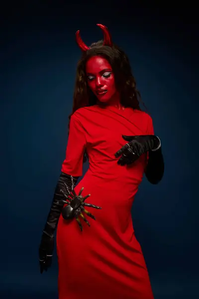 A captivating woman showcases her Halloween spirit in a dazzling red devil costume and makeup. — Stock Photo