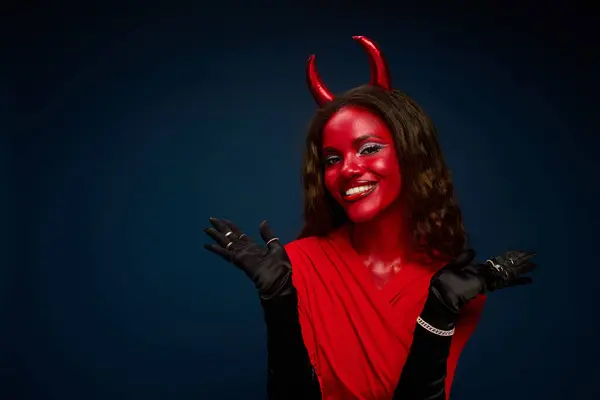 A stunning woman in a bright red devil costume radiates Halloween joy and playful spirit. — Stock Photo