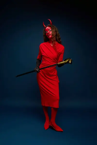 A stunning woman dressed as a devil strikes a playful pose while holding a staff. — Stock Photo