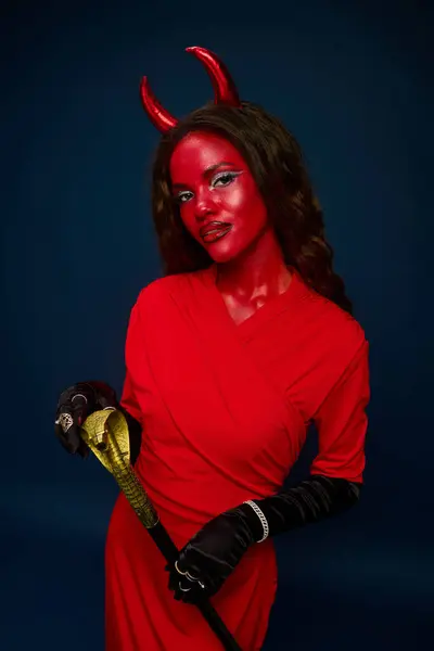 A stunning woman embraces the Halloween spirit in a bold red devil costume, complete with horns. — Stock Photo