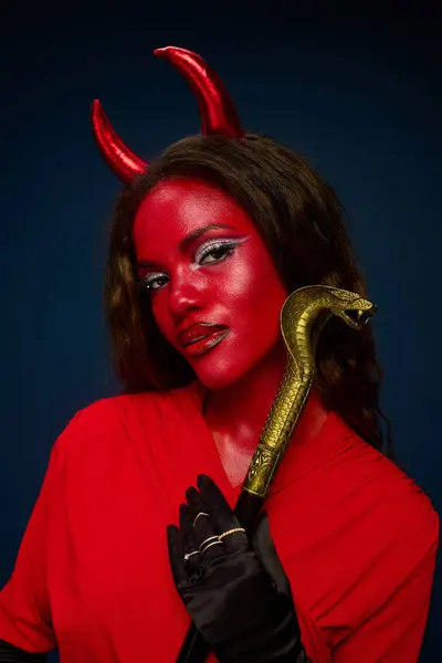 This woman embodies Halloween with a bold red outfit and devilish accessories. — Stock Photo