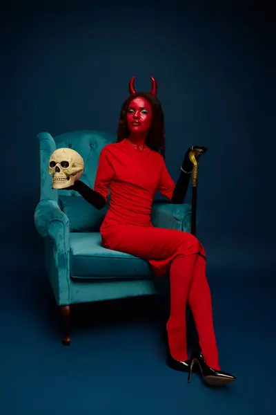The woman showcases her Halloween costume with vibrant colors, holding a skull and cane. — Stock Photo