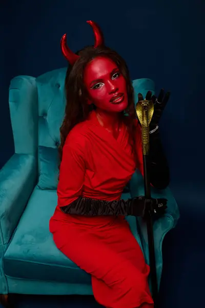 A beautiful woman dressed in a red Halloween costume showcases her creative makeup and outfit. — Stock Photo