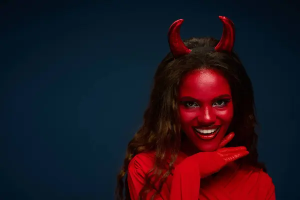 A striking woman dressed as a devil showcases her playful spirit with a beaming smile. — Stock Photo