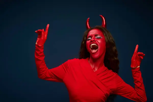 Vestita con un abito rosso radioso, una donna esprime gioiosamente il suo spirito di Halloween con entusiasmo. — Foto stock