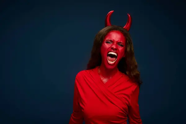 A woman in stunning red attire channels her inner devil, expressing excitement for Halloween. — Stock Photo