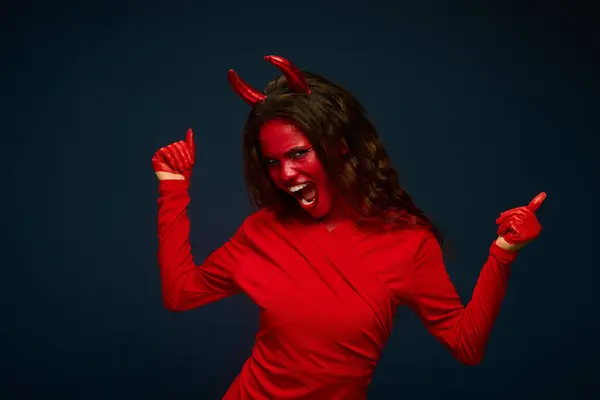 A striking woman dressed in a bold red devil outfit joyfully poses, exuding Halloween spirit. — Stock Photo