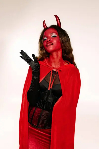 A striking woman dressed as a devil exudes confidence while posing playfully for Halloween. — Stock Photo