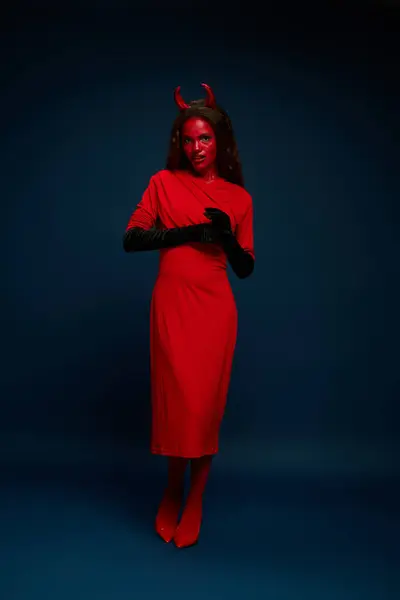 A captivating woman dressed as a devil showcases her bold Halloween outfit in a stylish pose. — Stock Photo