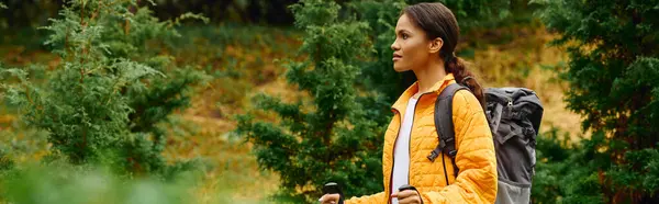 A young woman explores a colorful forest in autumn, embracing nature beauty on her hiking adventure. — Stock Photo