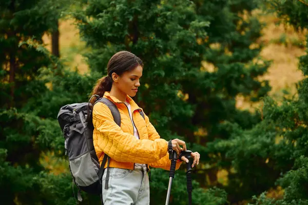In a beautiful forest of autumn colors, a young woman enjoys her hike, connecting with nature and adventure. — Stock Photo