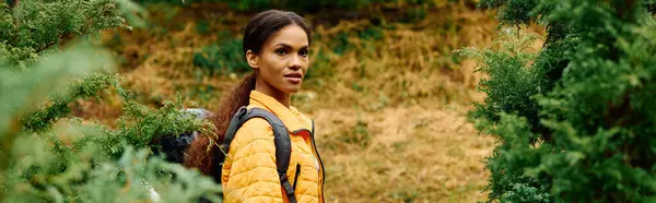 In una colorata foresta autunnale, una giovane donna esplora la natura, circondata da lussureggianti fogliame e tonalità calde. — Foto stock