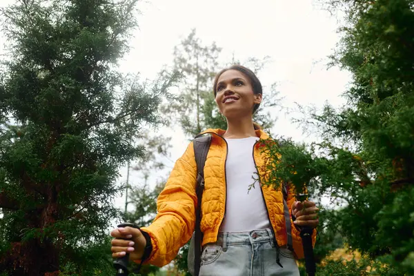 A joyful young woman hikes through a colorful autumn forest, embracing nature and adventure. — Stock Photo