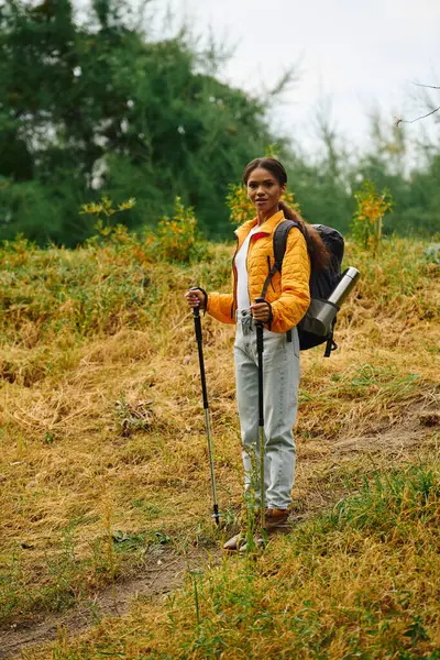 A young woman enjoys a refreshing hike in a forest adorned with vibrant autumn foliage, surrounded by nature. — Stock Photo