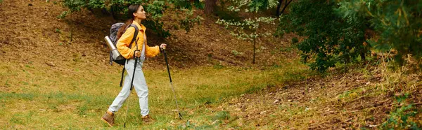A young African American woman is hiking through an autumn forest, enjoying the colorful foliage around her. — Stock Photo