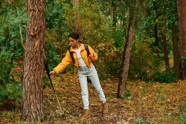 A young woman explores a vibrant autumn forest, surrounded by colorful foliage and tall trees. — Stock Photo