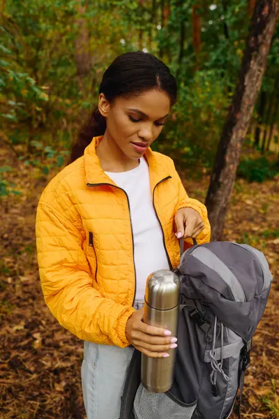 In una foresta colorata, una giovane donna si ferma per godersi la natura mentre esplora un sentiero autunnale sereno. — Foto stock