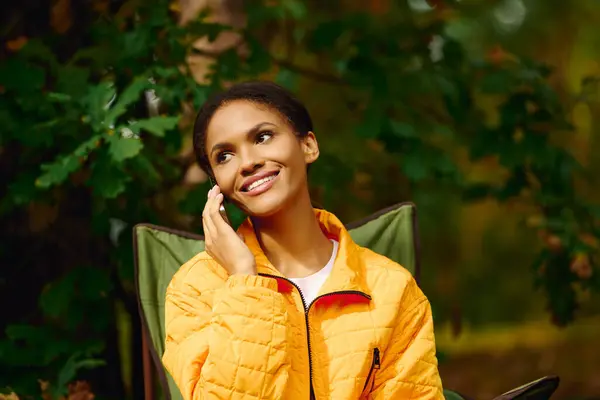 A young African American woman smiles while enjoying a hike in an autumn forest, embracing nature beauty. — Stock Photo