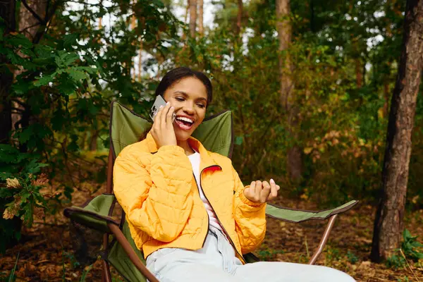 Eine junge Frau unterhält sich lebhaft im herbstlichen Wald, umgeben von buntem Laub und Natur. — Stockfoto