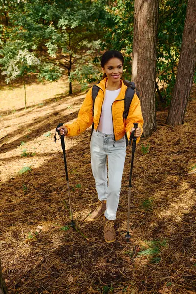 A young woman enjoys her hike in the forest, surrounded by stunning autumn colors and nature beauty. — Stock Photo