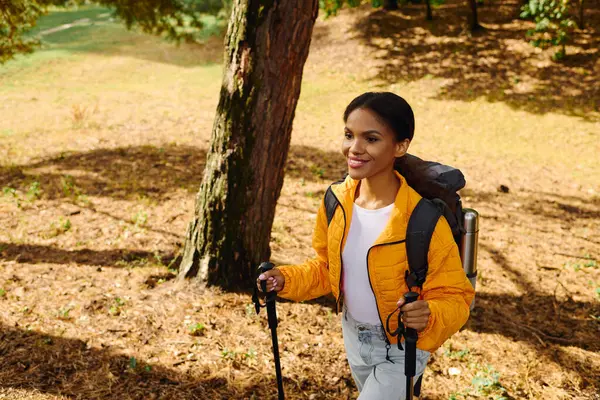 A young woman explores a colorful forest trail, surrounded by the warm hues of autumn foliage. — Stock Photo
