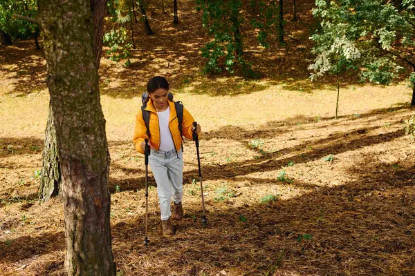A young African American woman hikes through a colorful autumn forest, embracing nature serenity and beauty. — Stock Photo