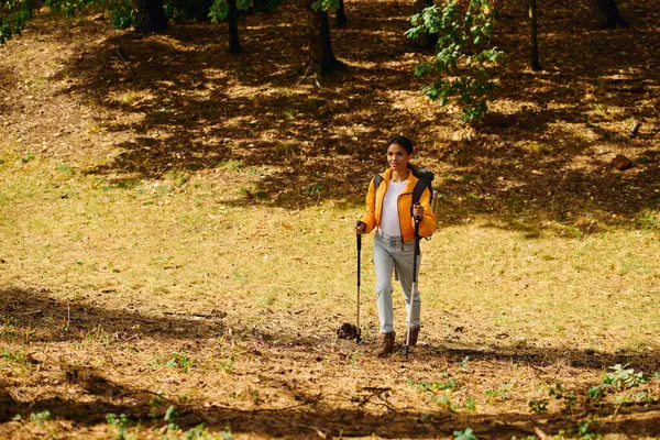 A young African American woman explores a colorful autumn forest while hiking and enjoying nature. — Stock Photo