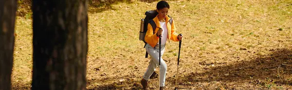 Una joven mujer disfruta de una caminata pacífica a través del vibrante follaje otoñal en un bosque tranquilo. - foto de stock