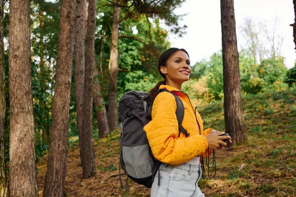 A young woman with a camera explores a colorful forest, embracing the beauty of autumn foliage and adventure. — Photo de stock