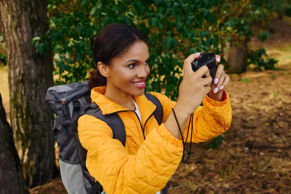 Joy radiates as a young woman captures the beauty of the autumn forest during her hike. — Stock Photo