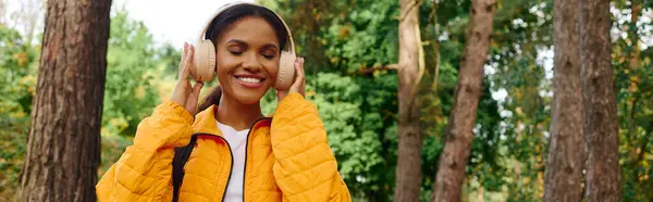 A young African American woman revels in the beauty of autumn while hiking through the serene forest. — Stock Photo