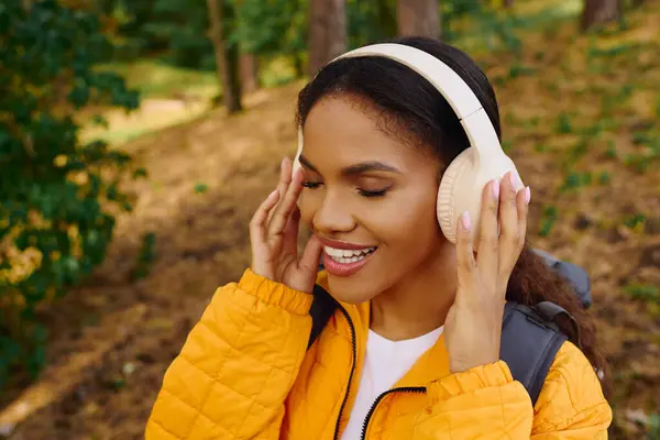 A young African American woman enjoys her hike through vibrant autumn foliage, immersed in nature tranquility. — Stock Photo