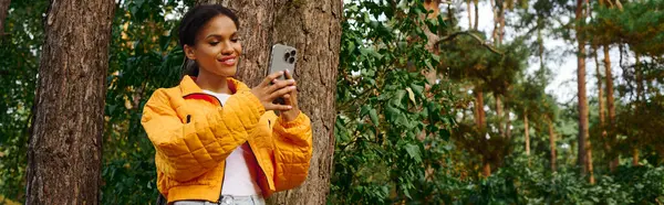 A young woman captures the beauty of autumn on her hike through a lush forest, embracing an active lifestyle. — Stock Photo