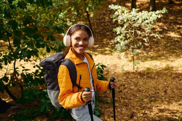 A spirited young woman embraces adventure while hiking in a colorful autumn forest, radiating joy. — Stock Photo