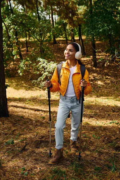 Una giovane donna afroamericana abbraccia la bellezza dell'autunno mentre cammina attraverso un sentiero sereno nella foresta. — Foto stock