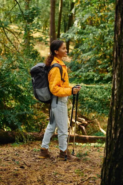 A young woman explores a colorful forest in autumn, embracing nature on her hiking journey. — Stock Photo