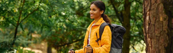 A young African American woman enjoys hiking amid colorful autumn leaves, embracing nature beauty. — Stock Photo