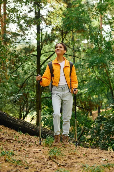 A young woman enjoys a hike in a colorful autumn forest, embracing nature with enthusiasm and joy. — Stock Photo
