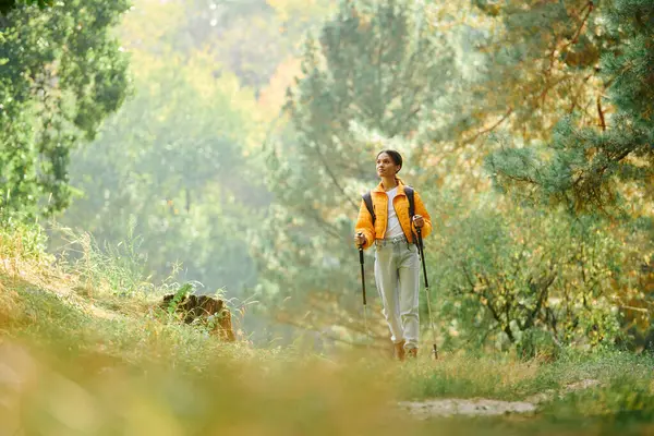 A young woman enjoys a refreshing hike through a colorful autumn forest, embracing nature beauty. — Stock Photo