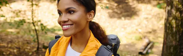 A young African American woman enjoys a refreshing hike amidst autumn foliage in a lush forest. — Stock Photo
