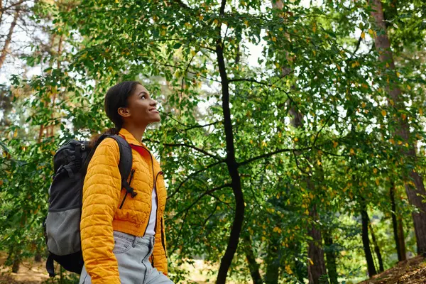 A young African American woman explores a lush forest on an autumn day, radiating joy and adventure. — Stock Photo