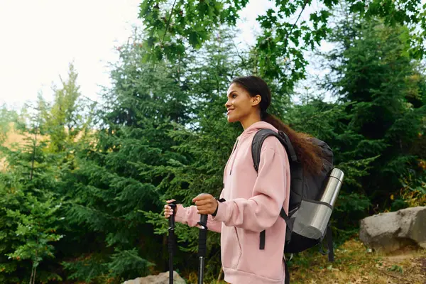 A young woman hikes through a colorful autumn forest, embracing the beauty of nature and adventure. — Stock Photo