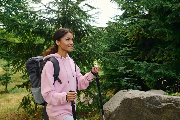 A young African American woman hikes through a colorful autumn forest, embracing adventure and nature. — Stock Photo