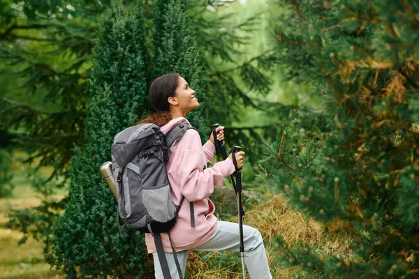 A young African American woman hikes through a colorful autumn forest, embracing the spirit of adventure. — Stock Photo