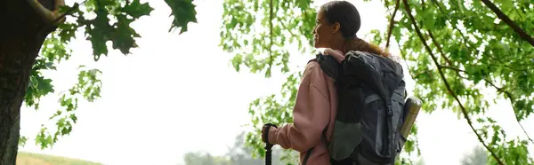 A young African American woman explores an autumn forest, enjoying the beauty of nature on her hike. — Stock Photo