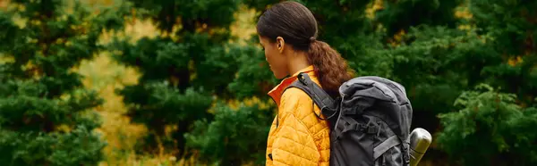 A young African American woman hikes through a colorful forest, surrounded by autumn leaves and nature beauty. — Stock Photo