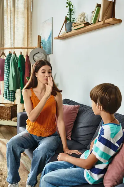 Una madre usa el lenguaje de señas para comunicarse amorosamente con su hijo con discapacidad auditiva en casa.. - foto de stock